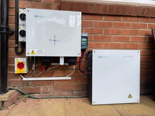 Electrical control panels mounted on a brick wall, with cables and warning labels.