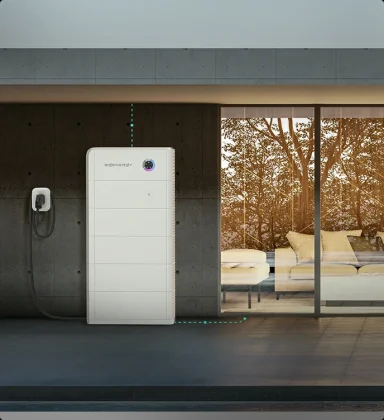 A modern home energy storage system next to large glass doors and a patio.