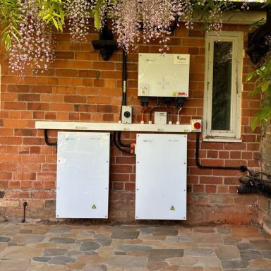Two white units mounted against a red brick wall, with pipes and a control panel above.