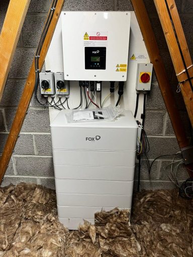 A control unit mounted on a wall in an attic, surrounded by insulation.