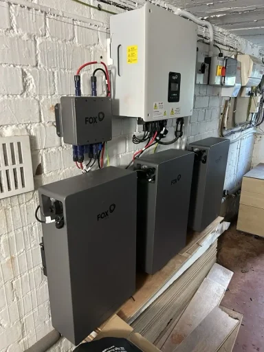 Four black power storage units mounted on a wall, connected to a control panel.