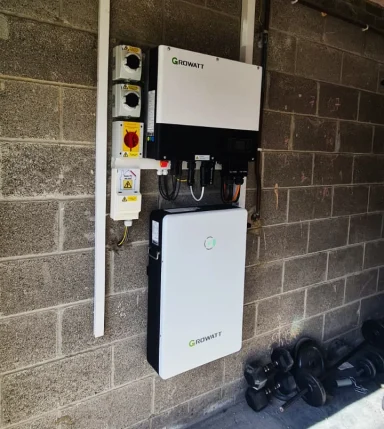 Two wall-mounted energy storage units with control panels in a garage setting.